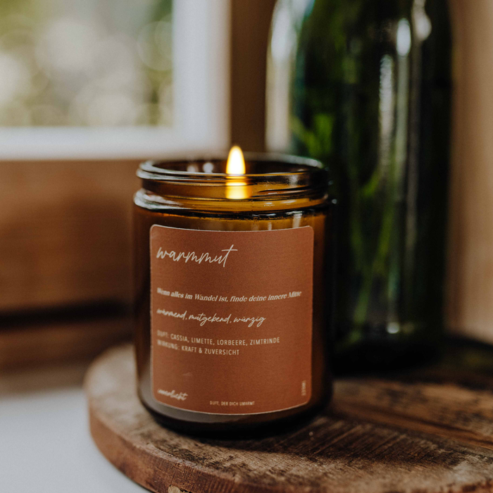 Duftkerze Warmmut von Innerlicht – handgegossene Aromakerze mit wohltuendem Duft aus Zimt, Lorbeer, Limette und Cassia, fotografiert in sanftem Licht auf einem Naturuntergrund.