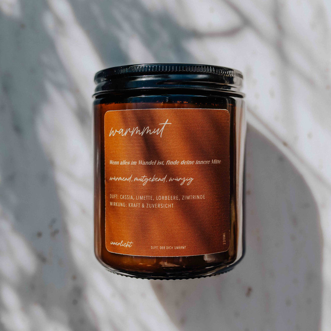 Duftkerze Warmmut von Innerlicht – handgegossene Aromakerze mit wohltuendem Duft aus Zimt, Lorbeer, Limette und Cassia, fotografiert in sanftem Licht auf einem Naturuntergrund.